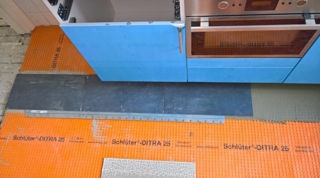eerste tegels over Ditra 25 polyethyleen mat op houten vloer in keuken